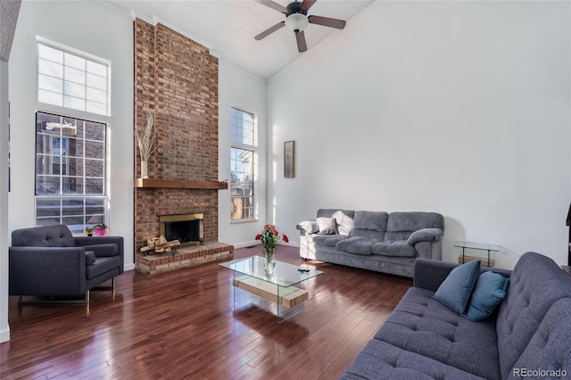 living room featuring baseboards, ceiling fan, hardwood / wood-style floors, a fireplace, and high vaulted ceiling