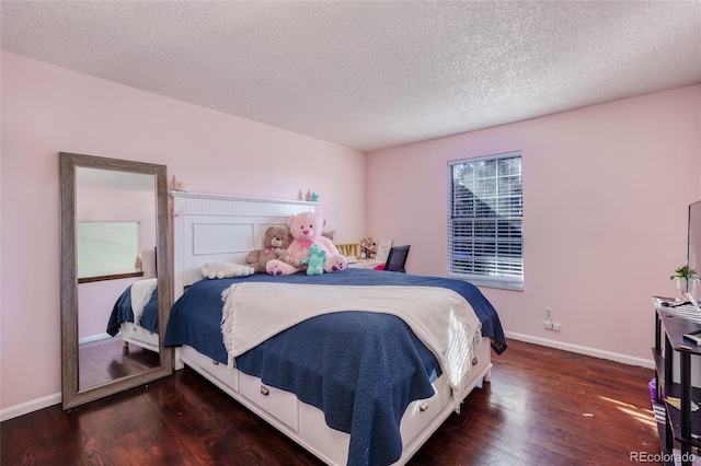 bedroom with a textured ceiling, baseboards, and wood finished floors