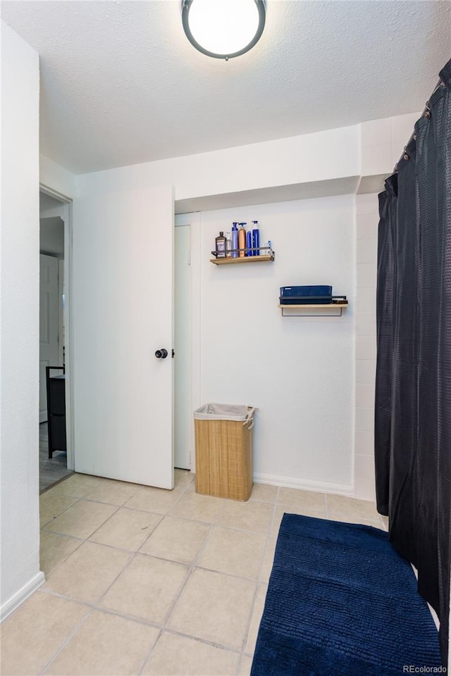 bathroom featuring baseboards, a textured ceiling, and tile patterned floors