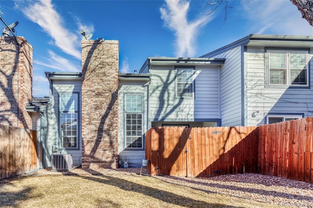 exterior space with a chimney, fence, and central AC