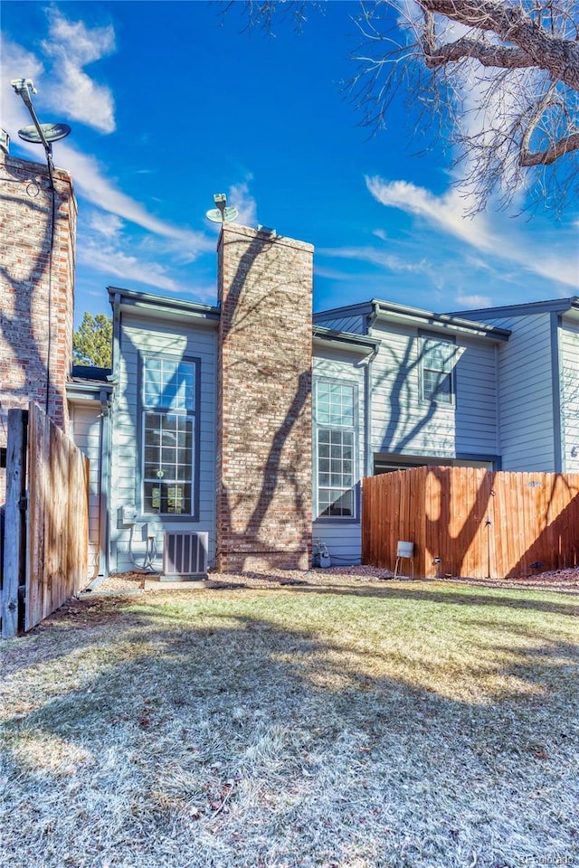 exterior space with a chimney, fence, central AC, and a yard