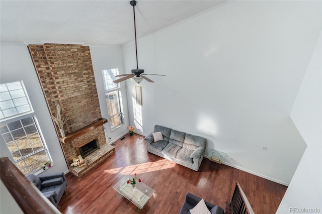 living room with baseboards, a towering ceiling, ornamental molding, wood finished floors, and a fireplace