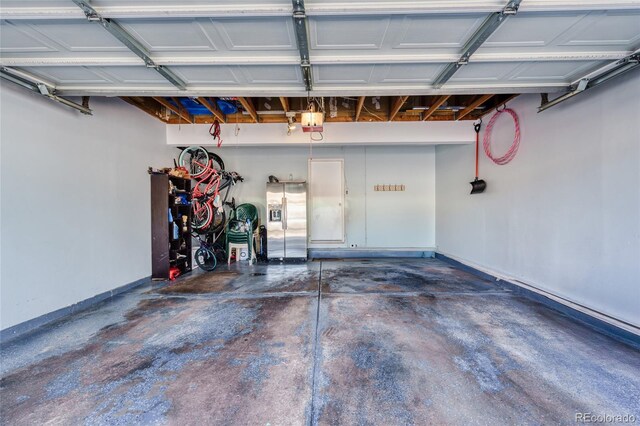 garage with stainless steel refrigerator with ice dispenser and a garage door opener