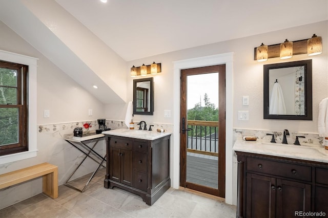 713 Rudi Ln, Golden, CO 80403 - full bath with healthy amount of natural light, tile walls, two vanities, a wainscoted wall, and lofted ceiling
