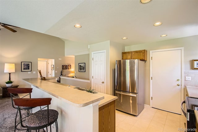 6114 Salvia Ln, Arvada, CO 80403 - kitchen with freestanding refrigerator, range with electric cooktop, a breakfast bar area, a peninsula, and light countertops
