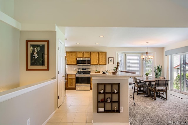 6114 Salvia Ln, Arvada, CO 80403 - kitchen with stainless steel appliances, brown cabinetry, a chandelier, light countertops, and pendant lighting