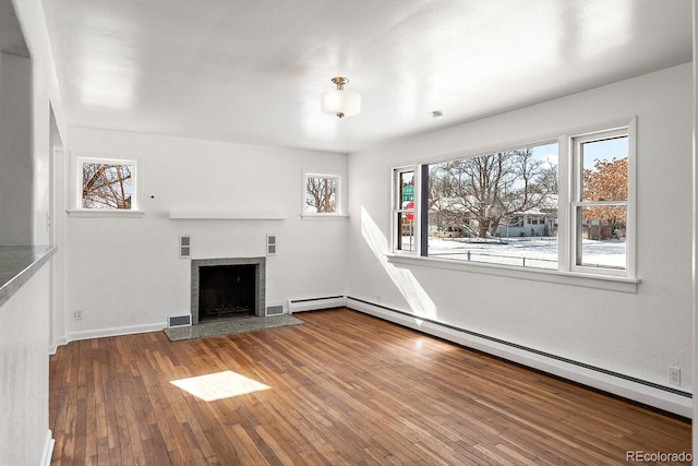 unfurnished living room with hardwood / wood-style floors, a baseboard radiator, and a tile fireplace