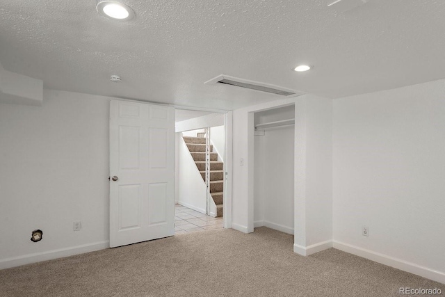 basement featuring light carpet and a textured ceiling