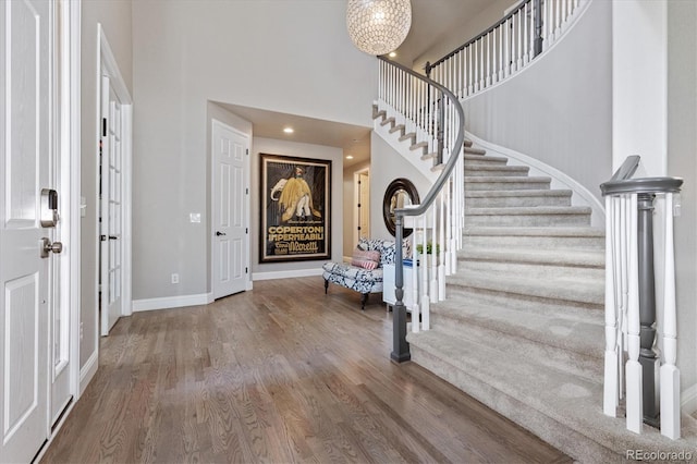 foyer with baseboards, an inviting chandelier, stairway, a high ceiling, and wood finished floors
