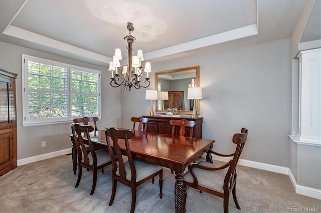 dining room with a tray ceiling, light colored carpet, and an inviting chandelier