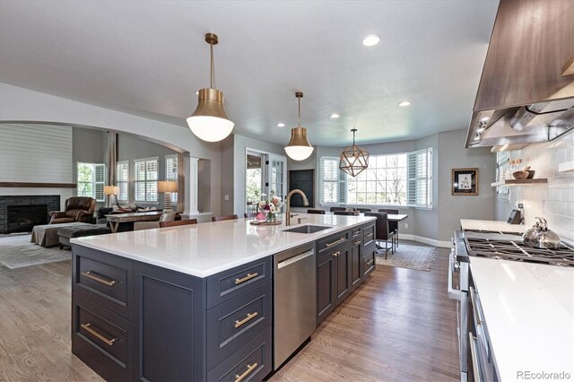 kitchen with light countertops, premium range hood, stainless steel appliances, arched walkways, and a sink