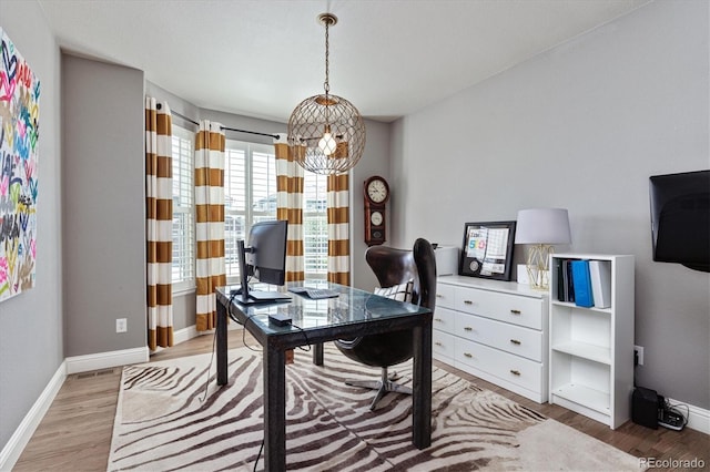 office area with light wood finished floors, a notable chandelier, and baseboards