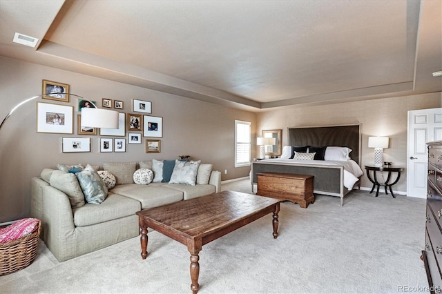 carpeted bedroom featuring a tray ceiling, baseboards, and visible vents