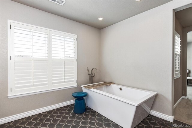 full bath featuring visible vents, baseboards, recessed lighting, and a soaking tub
