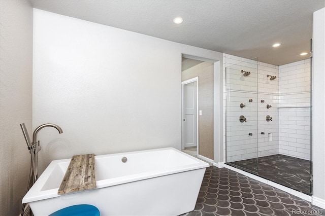 full bathroom featuring baseboards, a freestanding tub, a textured ceiling, recessed lighting, and a stall shower