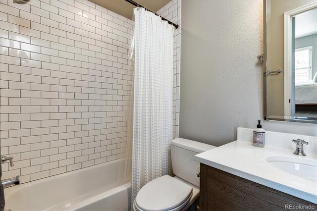 bathroom with a textured wall, shower / bathtub combination with curtain, vanity, and toilet