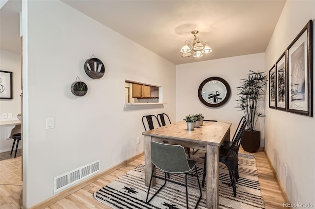 dining space featuring baseboards, visible vents, an inviting chandelier, and light wood-type flooring