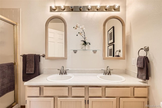 bathroom featuring double vanity, a sink, and a shower with door