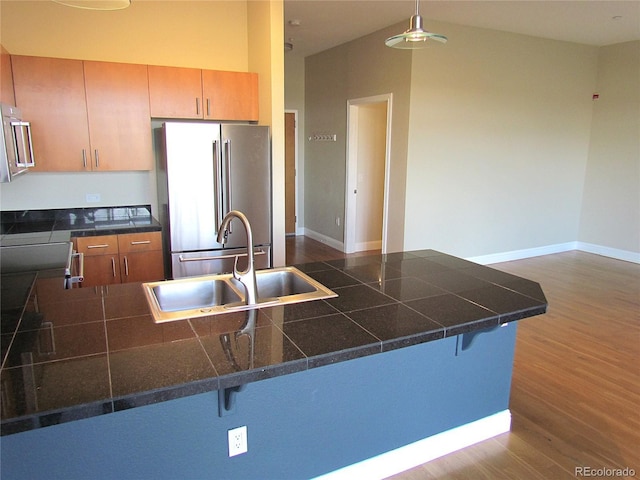 kitchen with high end fridge, a sink, a peninsula, a breakfast bar area, and dark wood-style flooring