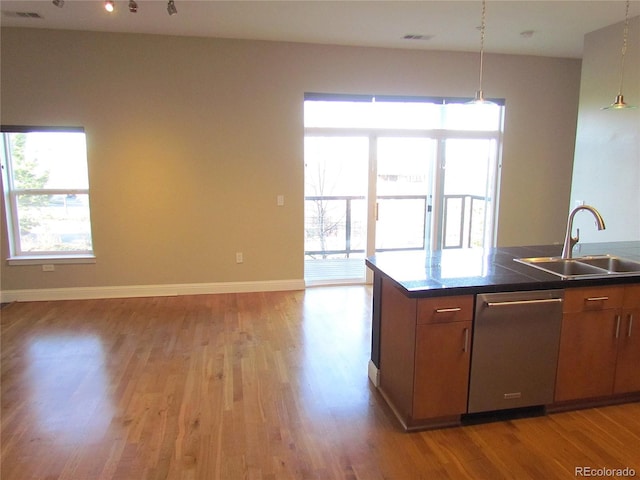 kitchen featuring light wood-style flooring, a sink, stainless steel dishwasher, open floor plan, and baseboards