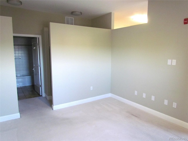 spare room featuring baseboards, visible vents, and light carpet