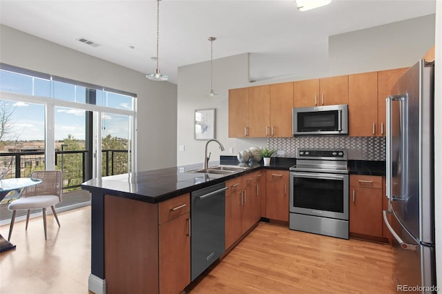 kitchen featuring stainless steel appliances, a peninsula, a sink, visible vents, and decorative backsplash