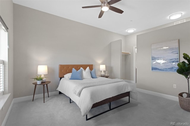 carpeted bedroom featuring a spacious closet, visible vents, a closet, baseboards, and ceiling fan