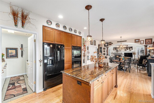 kitchen featuring black appliances, dark stone countertops, a notable chandelier, and light hardwood / wood-style floors