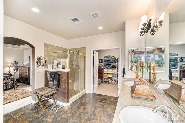 bathroom featuring a textured ceiling, shower with separate bathtub, and sink