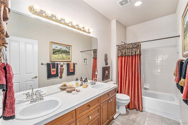 full bathroom featuring tile patterned floors, toilet, vanity, shower / bath combo with shower curtain, and a textured ceiling