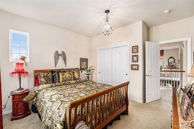 bedroom with a closet, carpet flooring, and an inviting chandelier