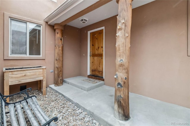 property entrance featuring visible vents and stucco siding