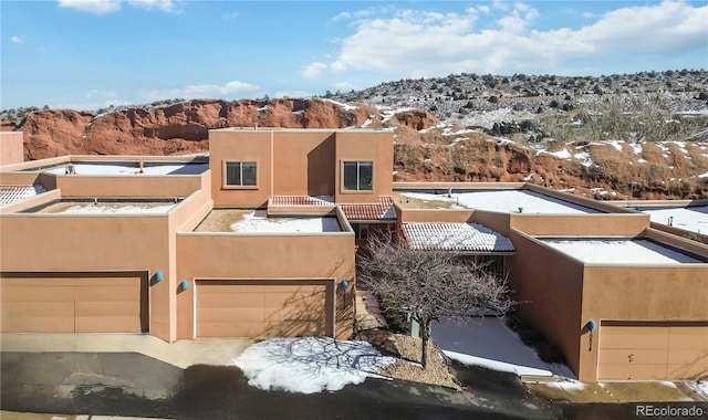 view of front facade with an attached garage, a mountain view, and stucco siding