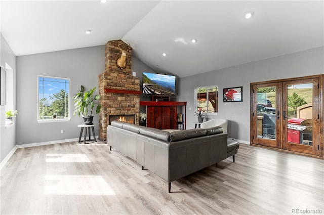 living room featuring a fireplace, light hardwood / wood-style flooring, lofted ceiling, and french doors