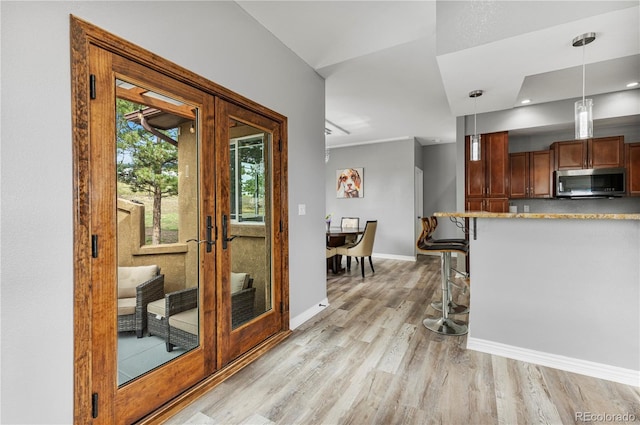 kitchen with decorative light fixtures, french doors, light hardwood / wood-style floors, and a breakfast bar