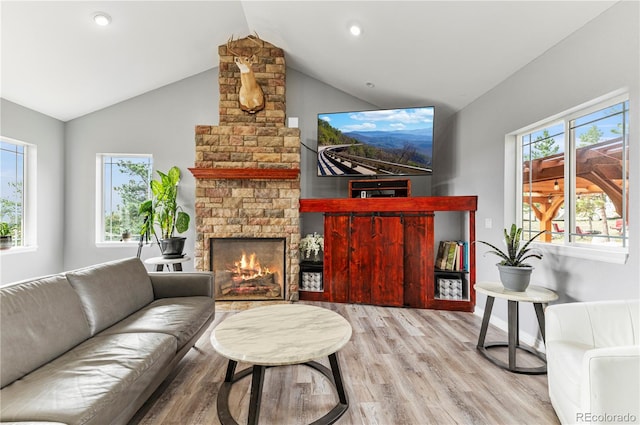 living room with a stone fireplace, light hardwood / wood-style flooring, and lofted ceiling