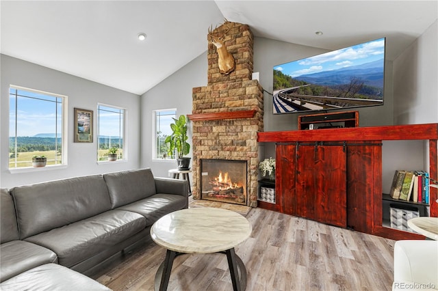 living room featuring a fireplace, light hardwood / wood-style floors, and vaulted ceiling