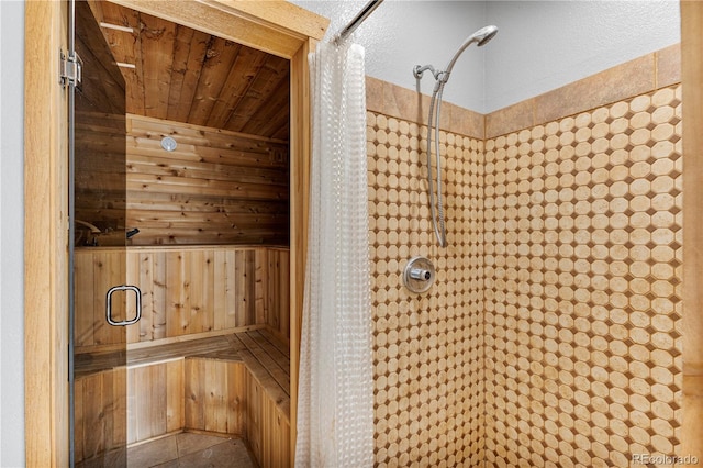 bathroom featuring a shower with door, wooden walls, and wood ceiling