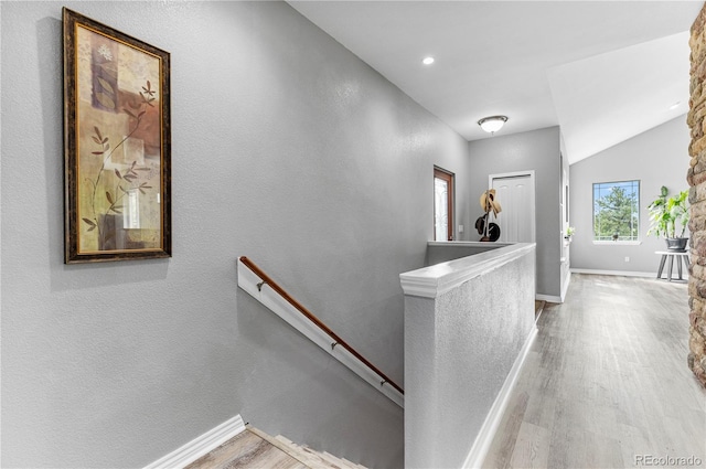 hallway with lofted ceiling and light wood-type flooring