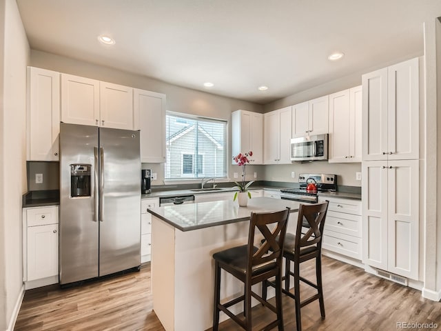 kitchen featuring stainless steel appliances, a kitchen bar, white cabinets, and a center island