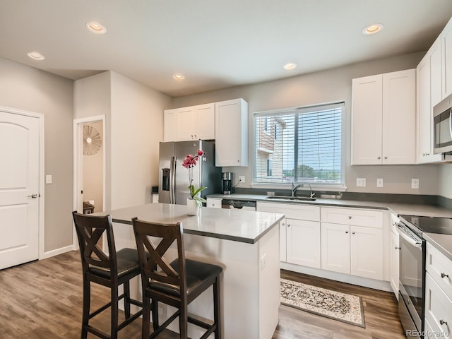 kitchen with appliances with stainless steel finishes, white cabinetry, a breakfast bar, and a center island