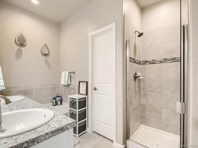 bathroom featuring tile patterned flooring, a tile shower, and vanity