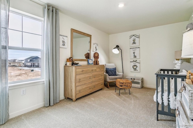 bedroom with multiple windows, a nursery area, and carpet