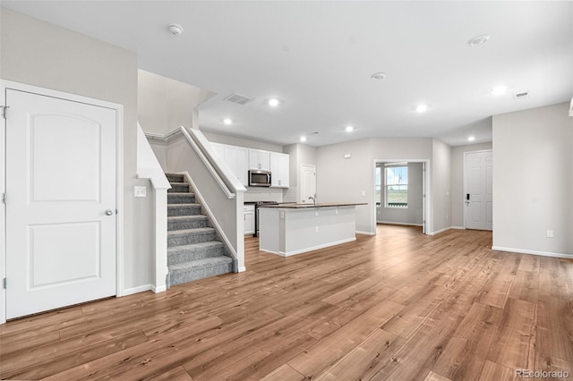 unfurnished living room featuring light wood-style floors, stairs, recessed lighting, baseboards, and visible vents