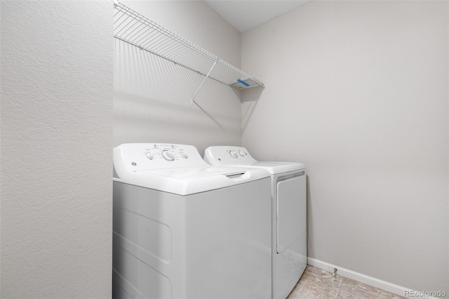 laundry area featuring washer and dryer, light tile patterned floors, laundry area, and baseboards