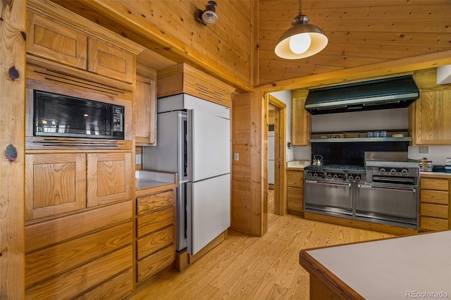 kitchen with white fridge, light hardwood / wood-style floors, hanging light fixtures, black microwave, and range hood