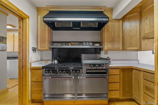 kitchen featuring extractor fan, separate washer and dryer, light hardwood / wood-style flooring, and gas stove