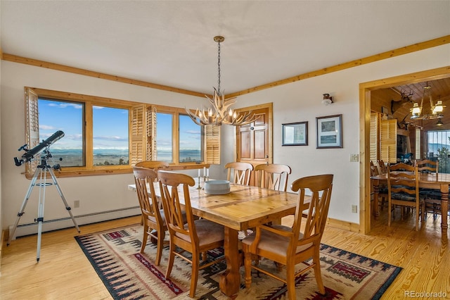 dining room featuring a wealth of natural light, an inviting chandelier, baseboard heating, and light hardwood / wood-style floors