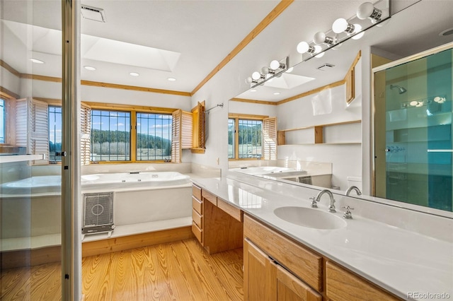 bathroom with ornamental molding, hardwood / wood-style floors, vanity with extensive cabinet space, separate shower and tub, and a skylight