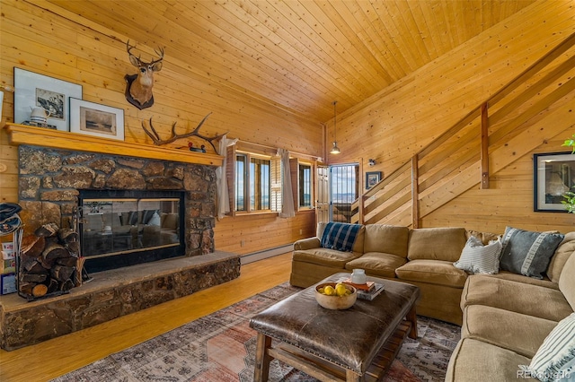 living room with a baseboard radiator, wood walls, hardwood / wood-style flooring, wooden ceiling, and a stone fireplace